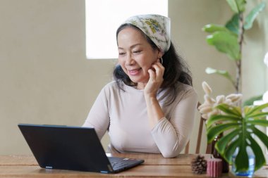 Yaz temalı bir kafede dizüstü bilgisayar kullanan yaşlı bir kadın. iş ve seyahat kavramı.