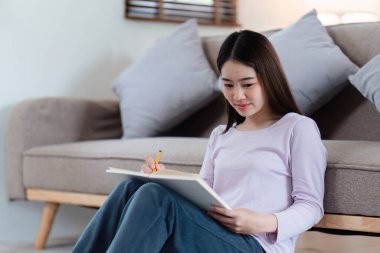 Çevrimiçi eğitim, e-öğrenme. Şık giyinmiş Asyalı bir kadın, dizüstü bilgisayar kullanıyor, online dersler dinliyor, notlar alıyor, evde online çalışmalar yapıyor..