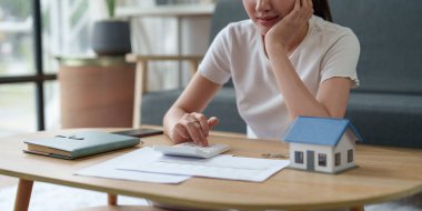 Asyalı muhasebe uzmanı ev faturalarını hesaplıyor, ev faturalarını inceliyor ve analiz ediyor ve vergi beyannamelerini dolduruyor..