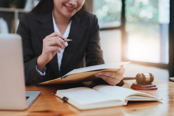Young lawyer in office Business woman and lawyers discussing contract papers with brass scale on wooden desk in office. Law, legal services, advice, Justice and real estate concept.