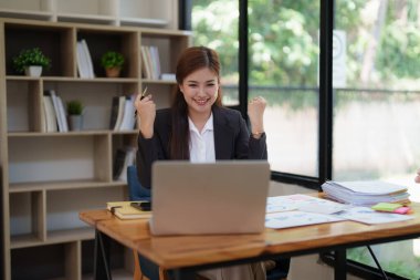 Asya İşadamları dizüstü bilgisayar kullanıyor ve zafer ve başarıyı kutluyor. İyi haberler ve başarıyı kutlayan bir iş var...