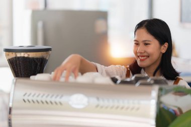 Kahve makinesiyle çalışırken gülümseyen Asyalı kafe sahibi ya da kahveci. Kadın küçük işletme sahibi yiyecek ve içecek..