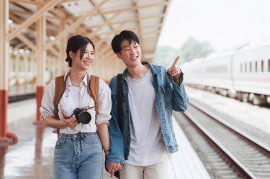Tren istasyonundaki Asyalı çift çok mutlu. Turizm ve yaz seyahatleri.