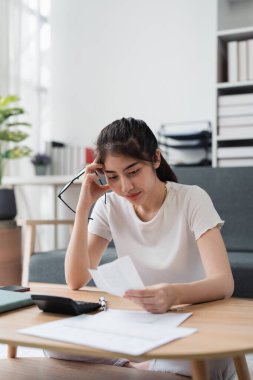 Asyalı muhasebe uzmanı ev faturalarını hesaplıyor, ev faturalarını inceliyor ve analiz ediyor ve vergi beyannamelerini dolduruyor..