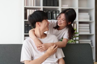 Sarılıp kanepede oturan Asyalı güzel bir çift. Romantik an, ilişkiler, aile kavramı.