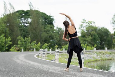Sağlıklı bir Asyalı kadın dışarıda koşmadan önce ısınır. Fitness kızı koşuyor. Açık hava parkında kadın egzersizi.