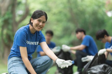 Çöp torbalarıyla park alanını temizleyen Asyalı gönüllüler. Ekoloji, hayır kurumu konsepti.