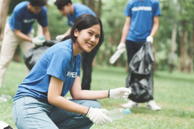 Çöp torbalarıyla park alanını temizleyen Asyalı gönüllüler. Ekoloji, hayır kurumu konsepti.