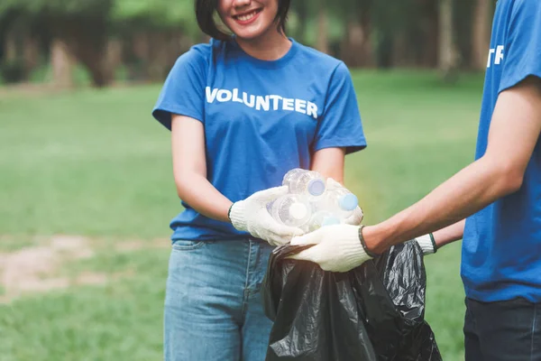 Çöp torbalarıyla park alanını temizleyen Asyalı gönüllüler. Ekoloji, hayır kurumu konsepti.