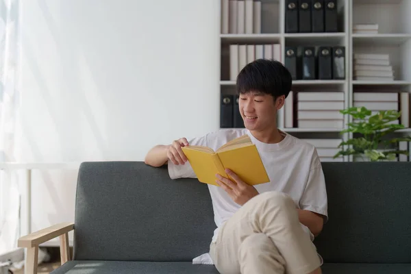 Aantrekkelijke Aziatische Man Rustend Comfortabele Woonkamer Leesboek Relax Bank Lifestyle — Stockfoto