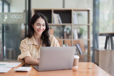 Dizüstü bilgisayarda çalışan ve belge, vergi, takas, araştırma, muhasebe ve mali danışman konsepti üzerinde çalışan muhasebeci kadın.