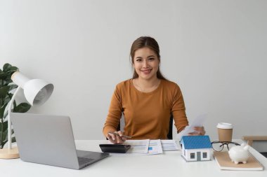 Asyalı muhasebe uzmanı ev faturalarını hesaplıyor, ev faturalarını inceliyor ve analiz ediyor ve vergi beyannamelerini dolduruyor..