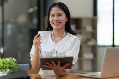 Asyalı bir kadın çalışıyor, dizüstü bilgisayar kullanıyor, finans şirketine rapor yazıyor. Muhasebe ve finansal kavram.