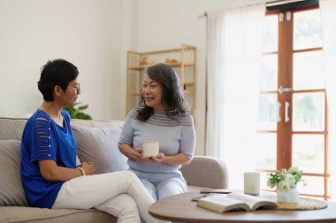 Sosyal medya ve oturma odasını kullanan Asyalı yaşlı kadın ve arkadaş. Yaşlılarla aynı evde video yayını, mutluluk ve sohbet..