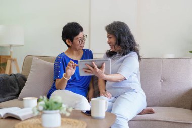 Sosyal medya ve oturma odasını kullanan Asyalı yaşlı kadın ve arkadaş. Yaşlılarla aynı evde video yayını, mutluluk ve sohbet..