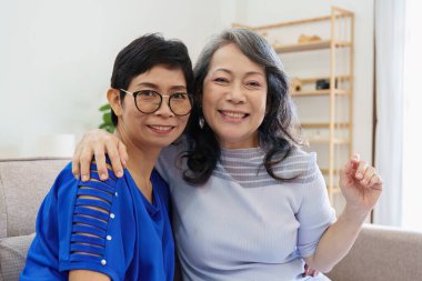 Sosyal medya ve oturma odasını kullanan Asyalı yaşlı kadın ve arkadaş. Yaşlılarla aynı evde video yayını, mutluluk ve sohbet..