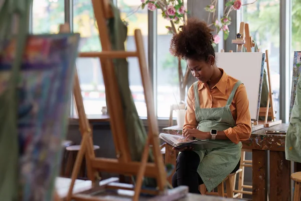 stock image Beautiful american african artist woman painting in art studio at the university classroom.