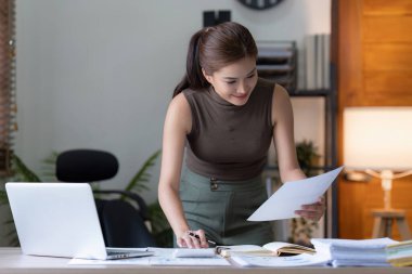 Dizüstü bilgisayarda çalışan ve belge, vergi, takas, araştırma, muhasebe ve mali danışman konsepti üzerinde çalışan muhasebeci kadın.