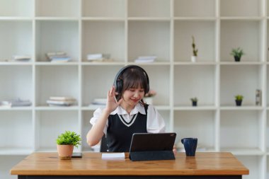 Çevrimiçi eğitim, e-öğrenme. Şık giyinmiş Asyalı bir kadın, dizüstü bilgisayar kullanıyor, online dersler dinliyor, notlar alıyor, evde online çalışmalar yapıyor..