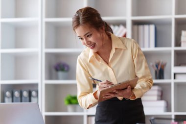 Dizüstü bilgisayarda çalışan ve belge, vergi, takas, araştırma, muhasebe ve mali danışman konsepti üzerinde çalışan muhasebeci kadın.