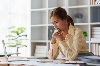 Asyalı iş kadını çalışırken stres hisseder, dizüstü bilgisayar kullanır, finans şirketine rapor verir. Muhasebe ve finansal kavram.