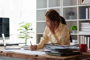 Asyalı iş kadını çalışırken stres hisseder, dizüstü bilgisayar kullanır, finans şirketine rapor verir. Muhasebe ve finansal kavram.