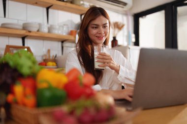 Bir kadın canlı mutfağında taze salata yerken sağlıklı beslenmenin zevkini keşfedin. Vücudunu besle ve lezzetli, besleyici yemeklerle sağlıklı bir yaşam tarzını benimse.
