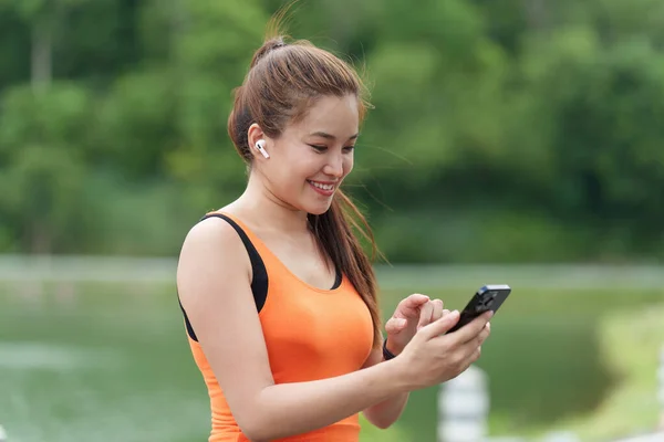 stock image Healthy Asian woman is warm up before jogging and checking sport app on smartwatch. Fitness girl running. Female exercising at outdoor park.