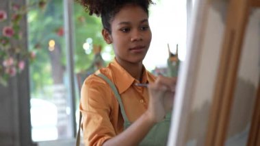 Güzel Amerikalı Afrikalı kadın üniversite sınıfındaki resim stüdyosunda resim yapıyor..