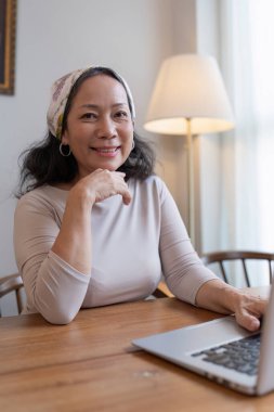 Yaz temalı bir kafede dizüstü bilgisayar kullanan yaşlı bir kadın. iş ve seyahat kavramı.