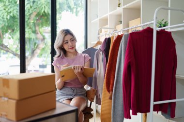 Asyalı kadın moda tasarımcısı bir moda stüdyosunda yeni bir elbise tasarlıyor..