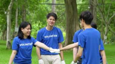 Genç Asyalı gönüllüler mutlu ve park alanında kutlama yapıyorlar. Ekoloji, hayır kurumu konsepti.