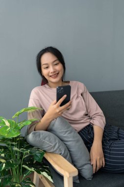 Genç bir kadın kanepede oturuyor ve arkadaşlarıyla oturma odasında sohbet ediyor..