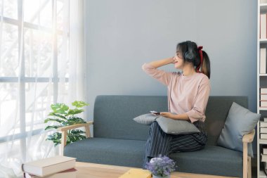 Oturma odasında kahve fincanı ve selfie ile kanepede oturan genç bir kadın..