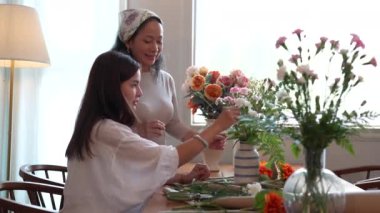 Başlangıç, küçük işletme, çiçekçi. Genç ve yaşlı kadın çiçekçi vazoya çiçek koyuyor. Yüksek kalite 4k görüntü