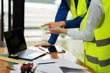 İnşaat mühendisleri ve mimarlar iş yerinde dizüstü bilgisayarla proje inşaatını tartıştılar..