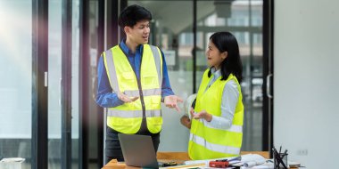 İnşaat mühendisleri ve mimarlar proje inşaatını ofiste birlikte tartışırlar..