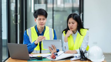İnşaat mühendisleri ve mimarlar proje inşaatını ofiste birlikte tartışırlar..