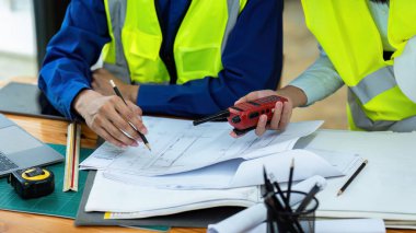 İnşaat mühendisleri ve mimarlar proje inşaatını ofiste ve telsiz başında tartışırlar..