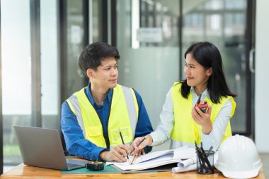 İnşaat mühendisleri ve mimarlar proje inşaatını ofiste ve telsiz başında tartışırlar..