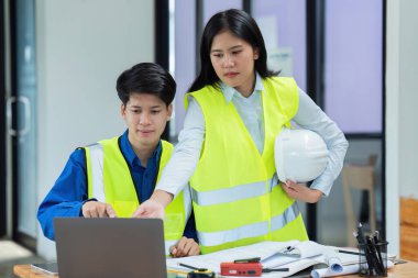 İnşaat mühendisleri ve mimarlar iş yerinde dizüstü bilgisayarla proje inşaatını tartıştılar..