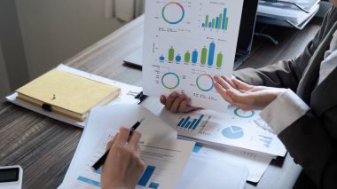 Şef ve çalışanın yakın çekimi ofiste aylık kazanç grafiğini tartışır..