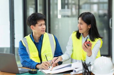 İnşaat mühendisleri ve mimarlar proje inşaatını ofiste ve telsiz başında tartışırlar..