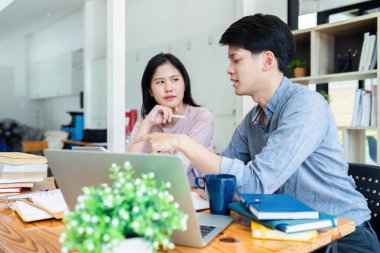 İki Asyalı öğrenci bir dizüstü bilgisayar ve kafede birlikte ders alıyorlar..