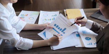 Şef ve çalışanın yakın çekimi ofiste aylık kazanç grafiğini tartışır..