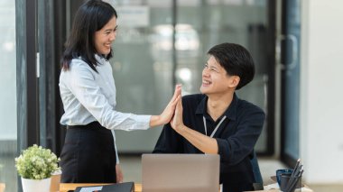 İş arkadaşları dizüstü bilgisayara bakıyor ve ofiste başarıyı kutluyor.