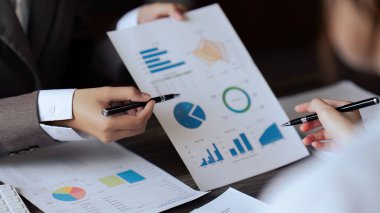 Şef ve çalışanın yakın çekimi ofiste aylık kazanç grafiğini tartışır..