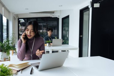 İş kadını ofis çalışanı cep telefonuyla konuşuyor, masada oturuyor, deftere bakıyor..