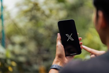 CHIANG MAI, THAILAND - 28 Temmuz 2023: Twitter logosu olan bir Apple iPhone tutan adam. Twitter, mikroblog ve ağ iletişimi için bir sosyal medya hizmetidir...