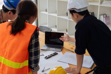 Bir grup mimar ve mühendis inşaat planlarını tartışıyor..
